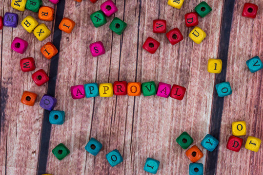aproval - word created with colored wooden cubes on desk.