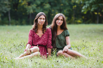 Two young smiling women sitting on grass