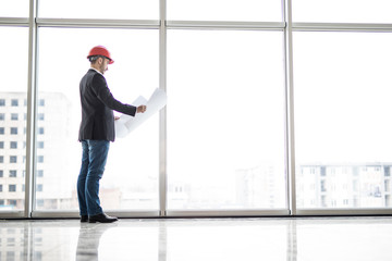 Builder engineer wear security helmet look at blueprint paper construction near panoramic windows