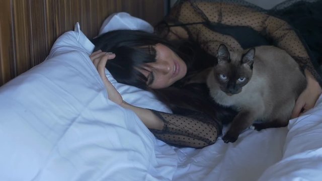 Female and cat lying on bed