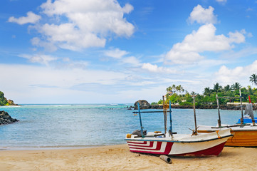 Naklejka na ściany i meble fishing boat on the sandy shore against a background the ocean and blue sky