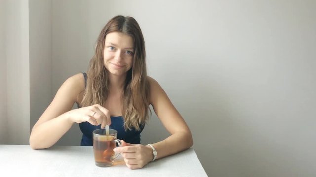 Portrait of a beautiful young woman without makeup with blonde hair prevents spoon tea