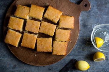Lemon drizzle cake, cut into squares on chopping board, overhead view