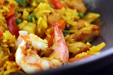 Udon stir-fry rice with shrimp and vegetables in wok pan on black burned stone background