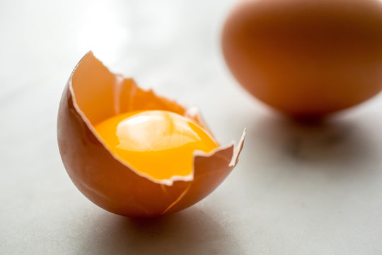 Yolk of egg in broken eggshell, close-up
