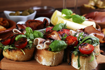 Italian antipasti wine snacks set. Cheese variety, Mediterranean olives, pickles, Prosciutto di Parma, tomatoes, artichokes and wine in glasses