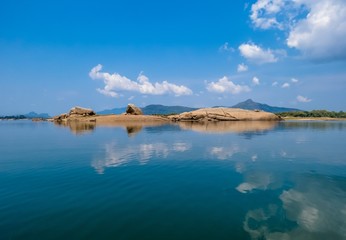 Reflection on Lake water of Beautiful yellow stone rock Island land with clouds and bluesky in Sri...