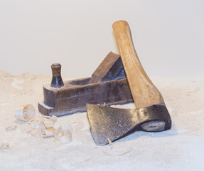 Old ax, planer and shavings on a light background.
