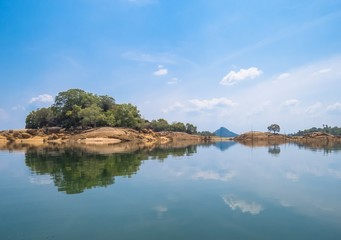 Fototapeta na wymiar Reflection on a Lake of Beautiful Island Trees land with rocks with bluesky and clouds in Sri Lanka