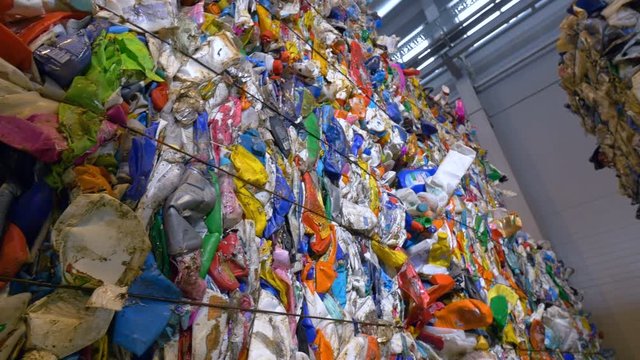 Recycling pet bottles collected into big stacks. Garbage sorting center. Dolly shot. 4K.