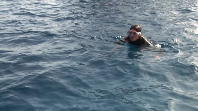 Woman diver dives into flippers underwater in Red Sea. Filming a movie. Young girl smiling at camera.