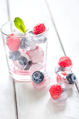 Frozen berries in glass for cocktail on wooden table background
