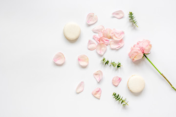 flat lay with petals and macaroons on white background top view