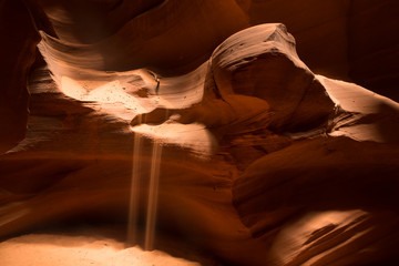 Sand falling from wavy sandstone in slot canyon