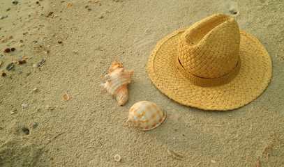 Fototapeta na wymiar Natural brown straw hat with beautiful natural seashells on the sand beach of Thailand