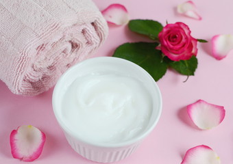 Fototapeta na wymiar Cosmetic creams and bath towel with pink flowers