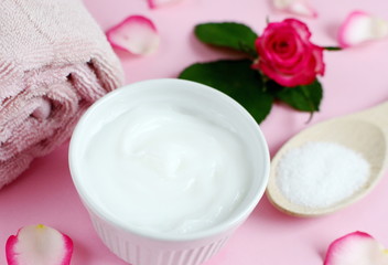 Fototapeta na wymiar Cosmetic creams and bath towel with pink flowers