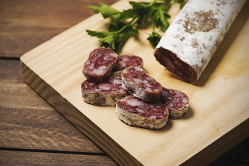 Close-up of cut fuet and a knife on a wooden board. Spanish sausage.