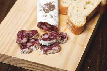 Fuet and bread  on a wooden board. Spanish sausage. Horizontal shoot.