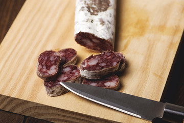 Fuet cut and knife on a wooden board. Spanish sausage. Horizontal shoot.