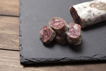 Fuet  on a slate plate. Spanish sausage. Horizontal shoot.