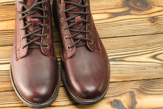 Stylish brown leather boots for men on wooden background, close-up view.