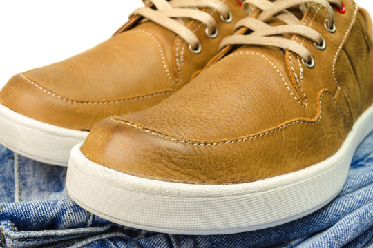 close-up view of tan color, leather sneakers on jeans pant.