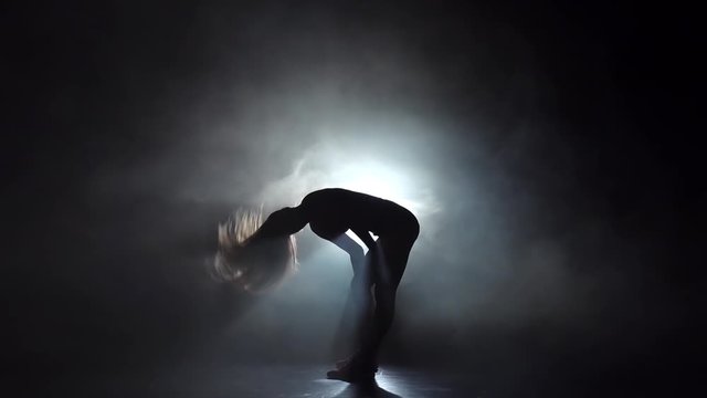 Silhouette girl dancing in smoky studio twerk dance. Slow motion