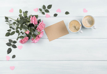 Roses with paper greeting card and coffee cup for Mothers day on background of wooden planks