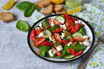 Vegetable salad with tomatoes, spinach and feta cheese on a concrete background.