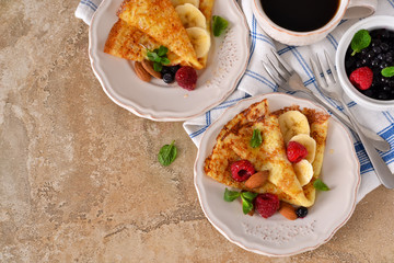 Homemade crepes with maple syrup and berries on a concrete background.