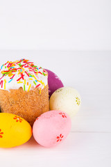 Easter cake with colorful eggs on white wooden background