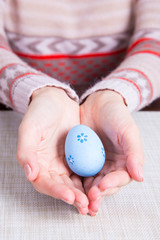 Fototapeta na wymiar Blue colored easter egg in female hands