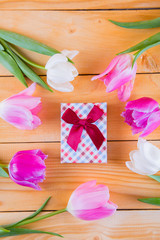 Bouquet of tender pink tulips with gift box on light wooden background