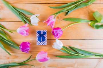 Bouquet of tender pink tulips with gift box on light wooden background