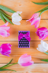 Obraz na płótnie Canvas Bouquet of tender pink tulips with gift box on light wooden background