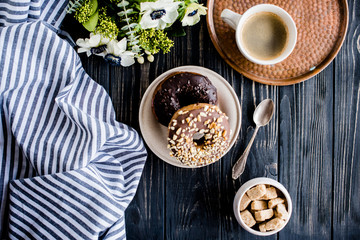 Cup of coffe and a chocolate donuts on black wood