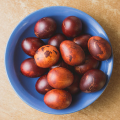 Easter eggs in the blue ceramic bowl. Painted brown with spots and cracks