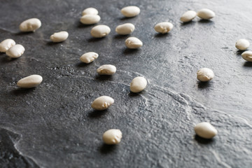 Fototapeta na wymiar White beans are scattered randomly on a black stone table from slate.