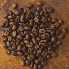 Brown coffee beans in circle shape, closeup of macro coffee beans for background and texture. On brown wooden board.
