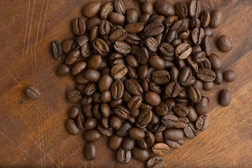 Brown coffee beans in circle shape, closeup of macro coffee beans for background and texture. On brown wooden board.