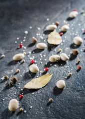 White beans and spices are scattered randomly on a black stone table from slate.