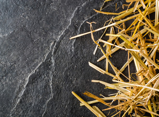 A bunch of yellow straw on the black background of an empty slab of slate.