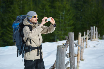 Fototapeta na wymiar hiker on the trail in the Carpathians mountains at winter. Man makes photo on the phone