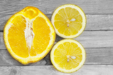 Fototapeta na wymiar Cut orange and lemon on a black and white wooden background.