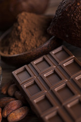 Chocolate bar, candy sweet, cacao beans and powder on wooden background