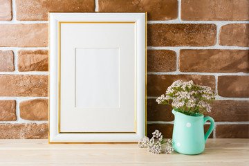Gold decorated frame mockup soft pink flowers exposed brick wall