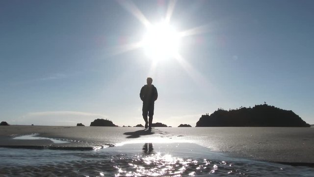 Model Released Person Walking Towards Camera At The Oregon Coast Along Sandy Beach On Clear And Sunny Day.