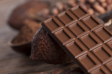 Chocolate bar, candy sweet, cacao beans and powder on wooden background