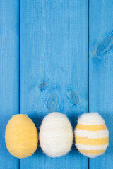 Easter eggs wrapped woolen string on blue wooden boards, copy space for text, decoration for Easter